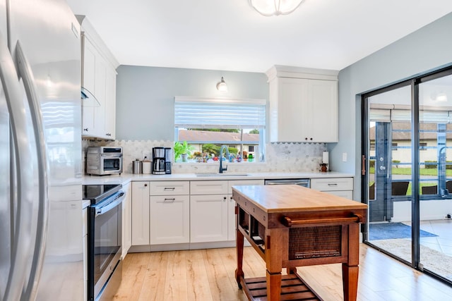 kitchen featuring sink, white cabinetry, stainless steel appliances, light hardwood / wood-style floors, and decorative backsplash