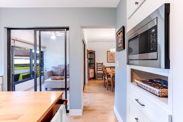 kitchen featuring light hardwood / wood-style floors, stainless steel microwave, and white cabinets