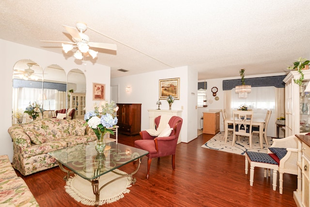 living room featuring a wealth of natural light, ceiling fan with notable chandelier, wood-type flooring, and a textured ceiling