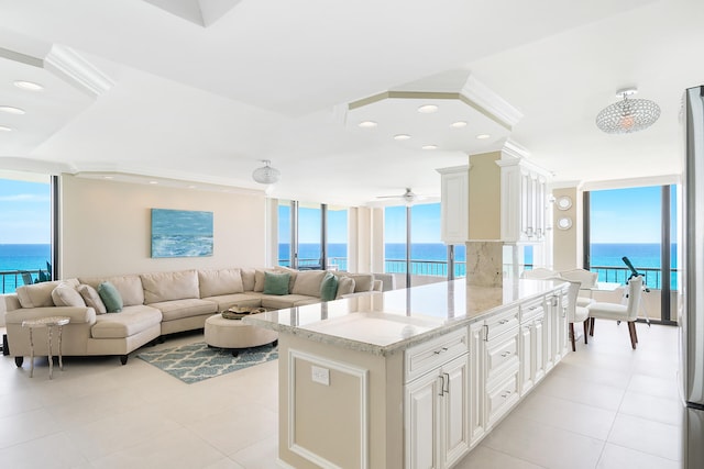 kitchen with a water view, light stone counters, a wealth of natural light, and light tile patterned floors