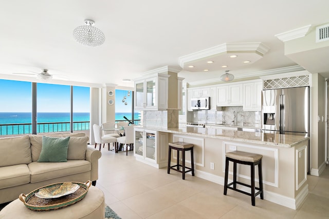 kitchen with appliances with stainless steel finishes, tasteful backsplash, white cabinets, a kitchen breakfast bar, and ceiling fan