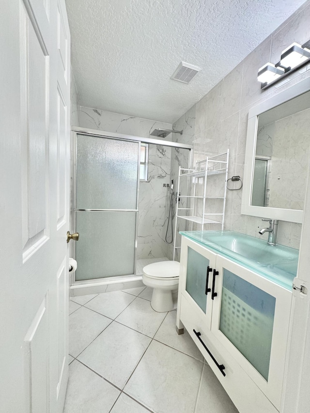 bathroom featuring a marble finish shower, visible vents, toilet, a textured ceiling, and vanity