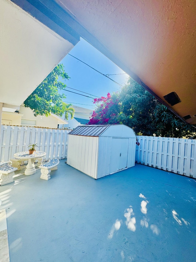 view of patio featuring an outdoor structure, a storage shed, and fence