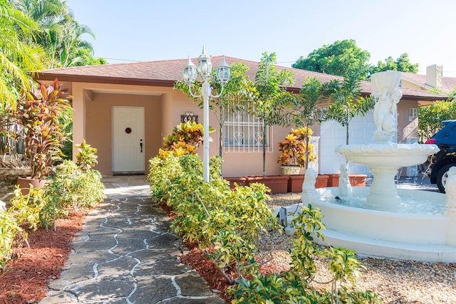 doorway to property featuring a shingled roof and stucco siding