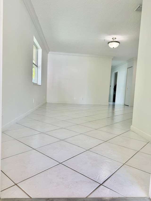 unfurnished room featuring light tile patterned floors, a textured ceiling, visible vents, baseboards, and ornamental molding