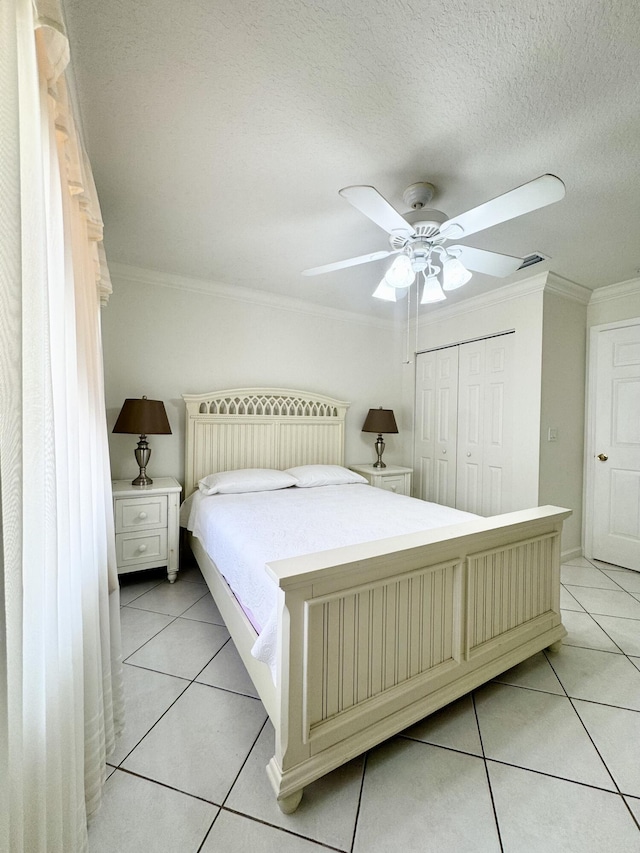 bedroom featuring light tile patterned floors, a textured ceiling, visible vents, ornamental molding, and a closet