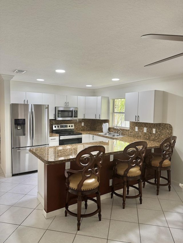 kitchen featuring visible vents, decorative backsplash, dark stone counters, appliances with stainless steel finishes, and a sink