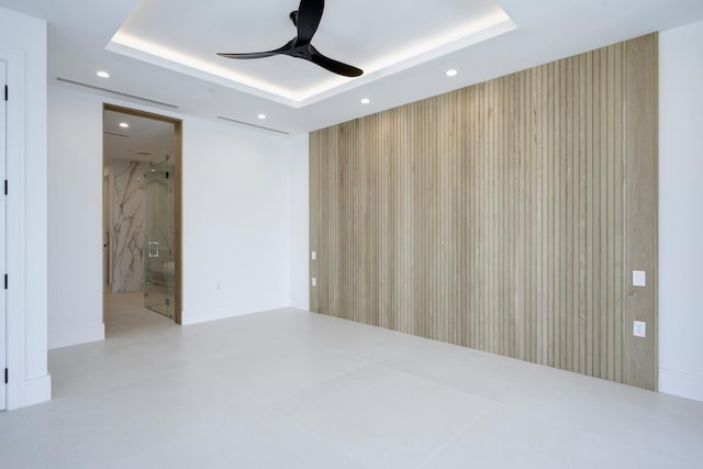 unfurnished room with ceiling fan and a tray ceiling