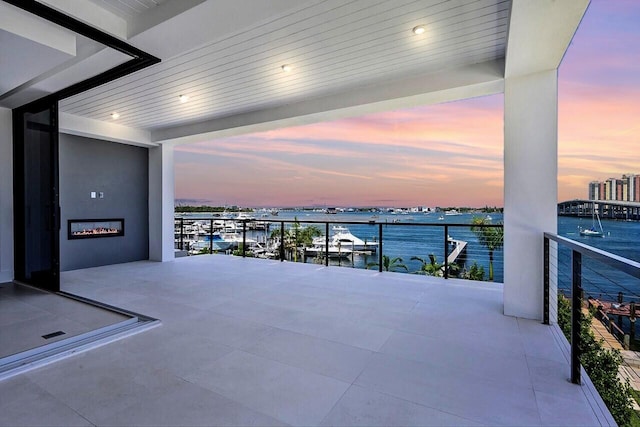 balcony at dusk featuring a water view