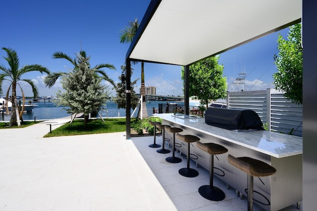 view of patio with a grill, a water view, and an outdoor bar