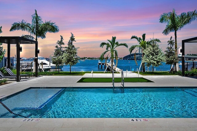 pool at dusk featuring a water view