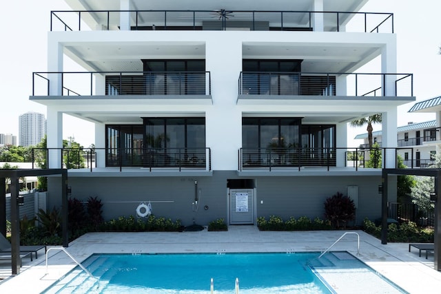 back of house featuring a patio area, a community pool, and a balcony