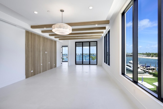 empty room with a water view, plenty of natural light, and beamed ceiling