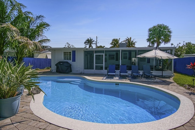 view of pool featuring a patio area, a sunroom, and grilling area