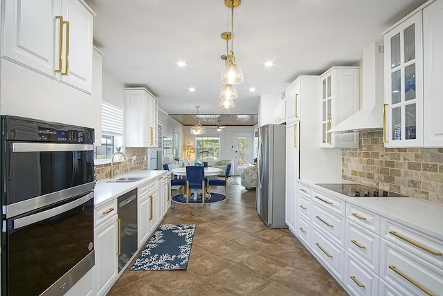 kitchen with black appliances, white cabinets, wall chimney exhaust hood, and sink