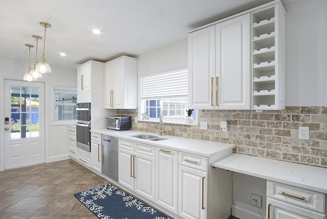 kitchen featuring stainless steel appliances, sink, white cabinets, and decorative light fixtures