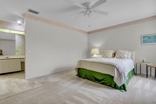 carpeted bedroom with ensuite bath, ceiling fan, and a textured ceiling