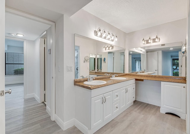 bathroom with hardwood / wood-style flooring, a textured ceiling, and vanity