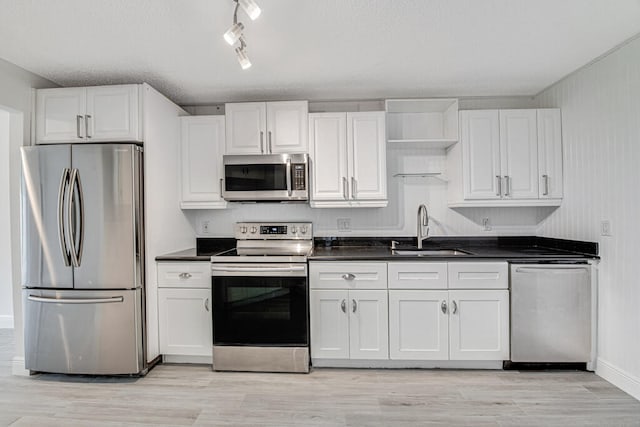 kitchen featuring appliances with stainless steel finishes, light hardwood / wood-style floors, white cabinetry, and sink