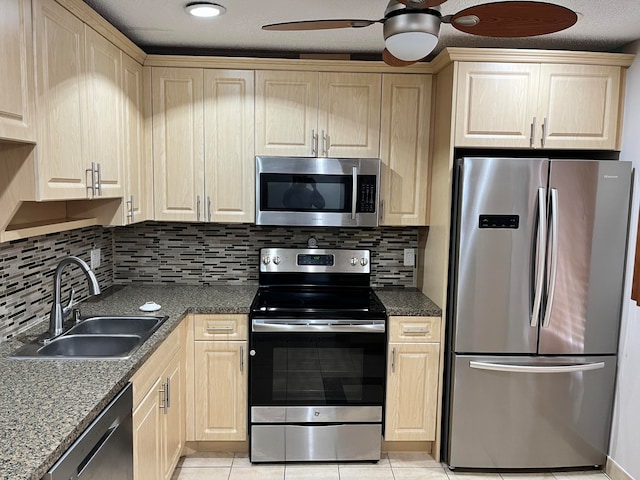 kitchen featuring appliances with stainless steel finishes, decorative backsplash, sink, and ceiling fan