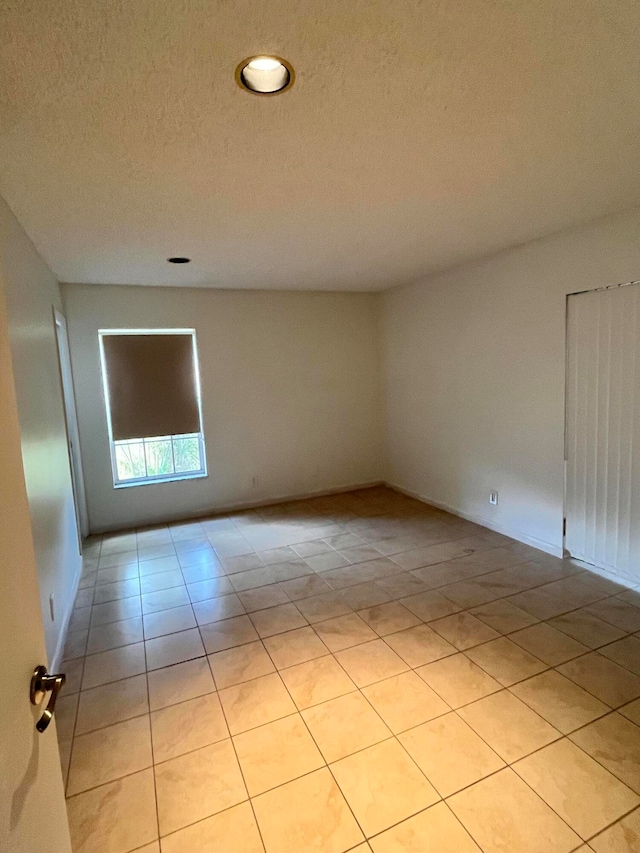 tiled spare room featuring a textured ceiling