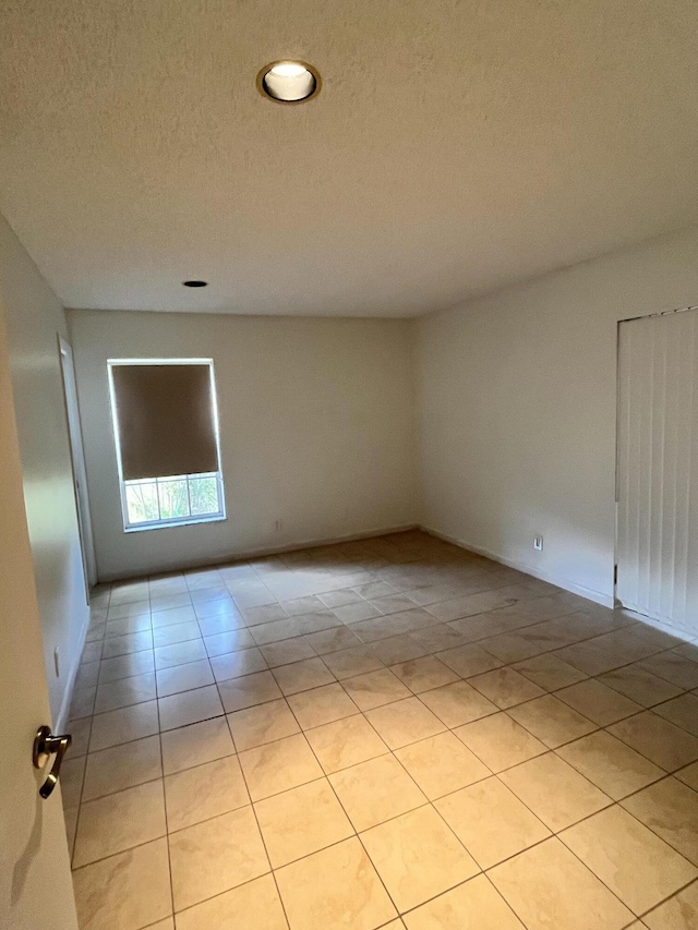 tiled empty room featuring a textured ceiling