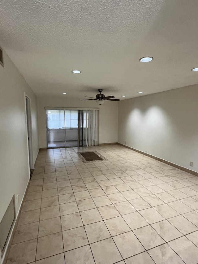 empty room with light tile patterned floors, a textured ceiling, and ceiling fan