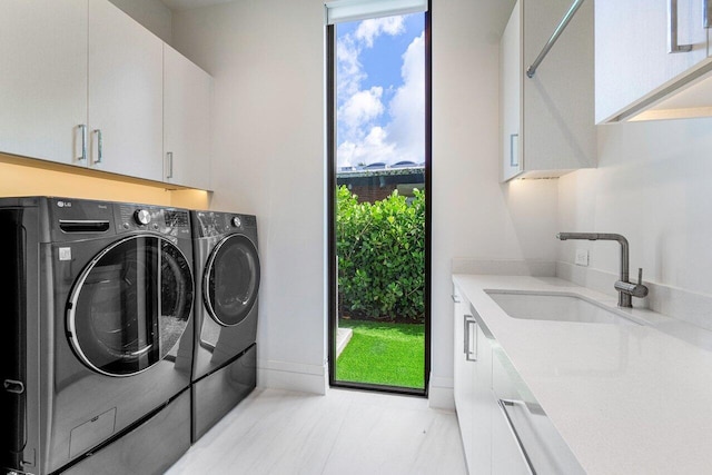 laundry area featuring cabinets, separate washer and dryer, sink, and a wealth of natural light