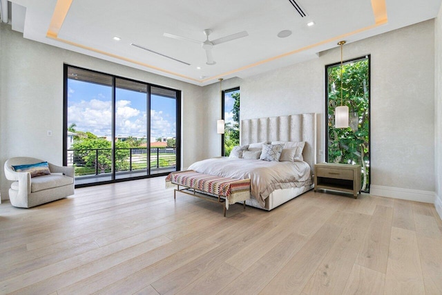 bedroom featuring ceiling fan, access to exterior, a raised ceiling, and light hardwood / wood-style flooring