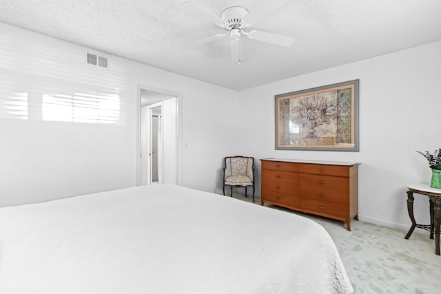 bedroom with ceiling fan, a textured ceiling, and light carpet