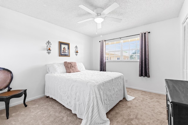 bedroom featuring ceiling fan, light colored carpet, and a textured ceiling