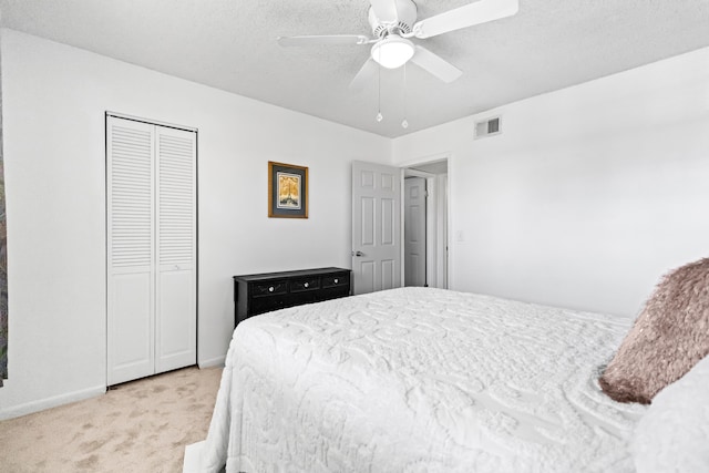 carpeted bedroom with a textured ceiling, ceiling fan, and a closet