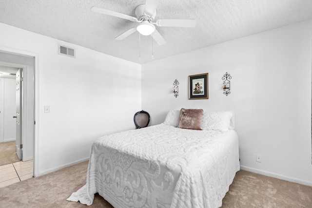 carpeted bedroom featuring ceiling fan and a textured ceiling