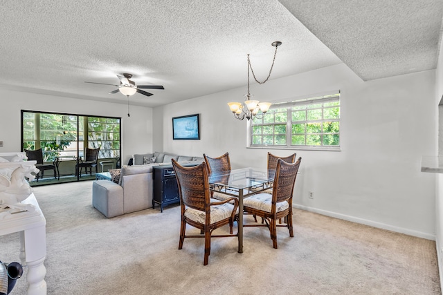 carpeted dining space featuring a healthy amount of sunlight, ceiling fan with notable chandelier, and a textured ceiling