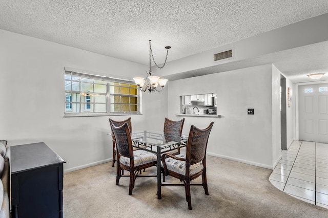 dining space featuring a textured ceiling, sink, light colored carpet, and a notable chandelier