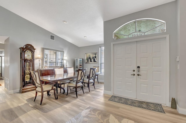 entryway with light hardwood / wood-style flooring, a wealth of natural light, high vaulted ceiling, and a textured ceiling