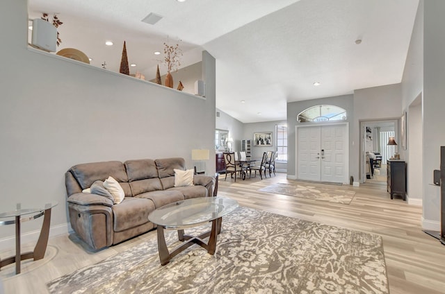 living room with high vaulted ceiling and light hardwood / wood-style floors