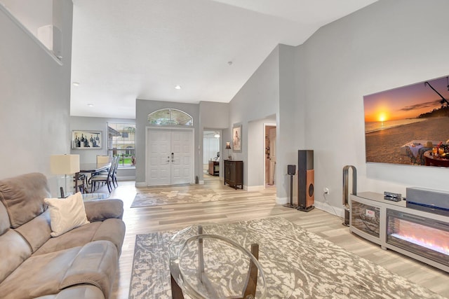 living room featuring high vaulted ceiling and light hardwood / wood-style flooring