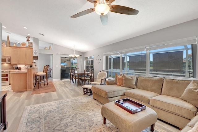 living room featuring ceiling fan with notable chandelier, lofted ceiling, light hardwood / wood-style floors, and a wealth of natural light