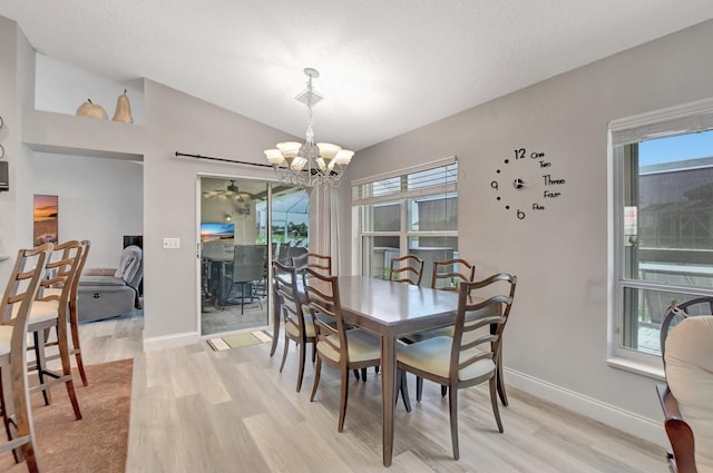 dining room featuring lofted ceiling, plenty of natural light, a notable chandelier, and light wood-type flooring