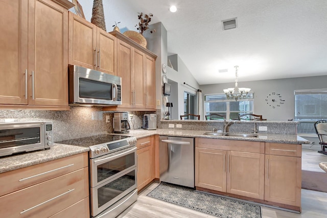 kitchen with sink, tasteful backsplash, appliances with stainless steel finishes, kitchen peninsula, and pendant lighting