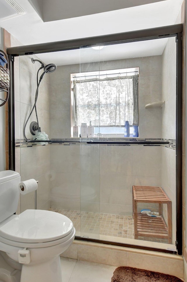 bathroom featuring walk in shower, toilet, and tile patterned flooring