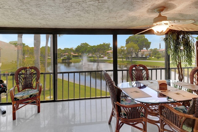 sunroom with ceiling fan and a water view