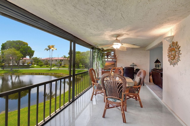 sunroom / solarium featuring a water view and ceiling fan