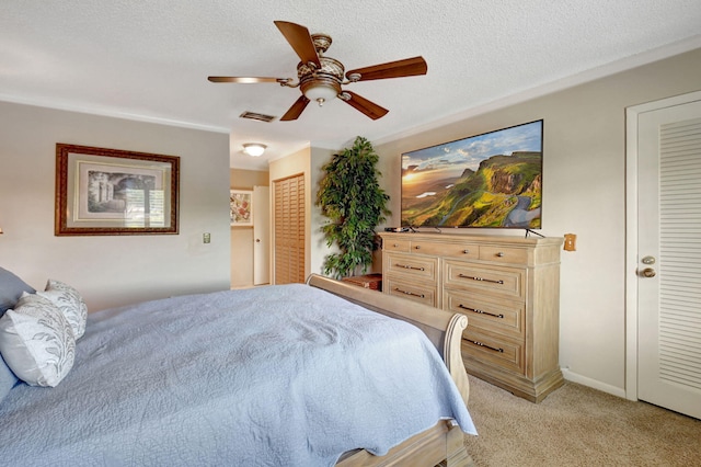 bedroom with ceiling fan, light carpet, and a textured ceiling