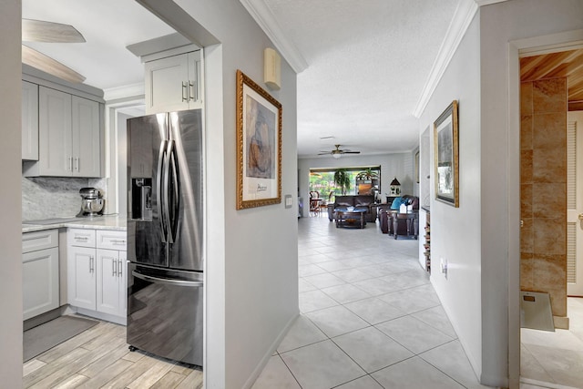 kitchen with backsplash, light tile patterned floors, stainless steel fridge with ice dispenser, and ornamental molding