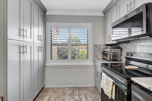 kitchen featuring decorative backsplash, electric range, gray cabinets, and ornamental molding