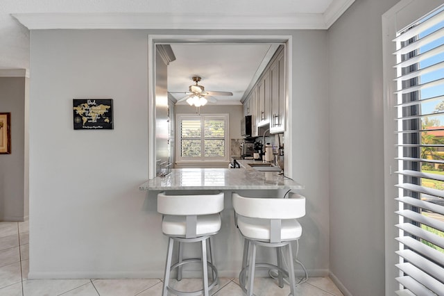 kitchen with sink, light tile patterned floors, kitchen peninsula, and a healthy amount of sunlight