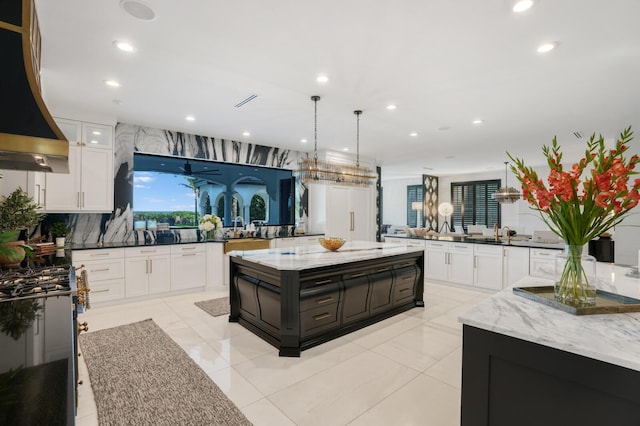 kitchen featuring decorative light fixtures, white cabinets, custom exhaust hood, kitchen peninsula, and a spacious island