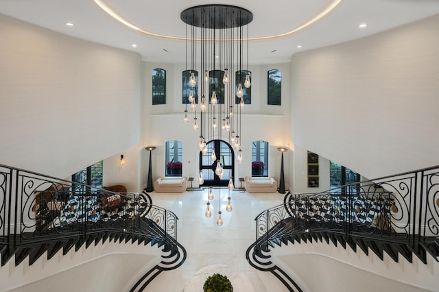 stairs with a towering ceiling, a healthy amount of sunlight, and a tray ceiling